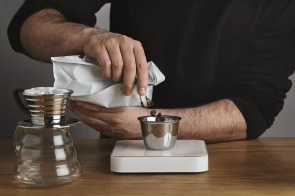 Hombre y una balanza buscando Cuantas tazas se necesitan para 1 kg de granos de café a granel España